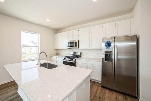 kitchen with an island with sink, stainless steel appliances, white cabinetry, and sink