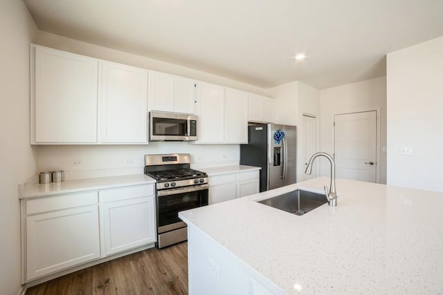 kitchen featuring sink, light stone countertops, appliances with stainless steel finishes, white cabinetry, and wood-type flooring