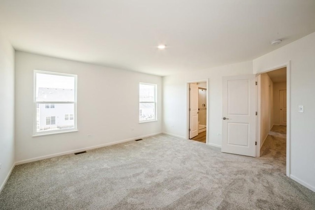 unfurnished bedroom featuring ensuite bathroom and light colored carpet