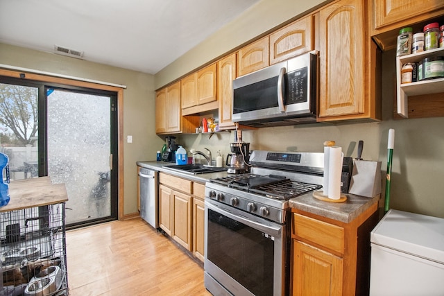 kitchen with sink, light wood-type flooring, and appliances with stainless steel finishes