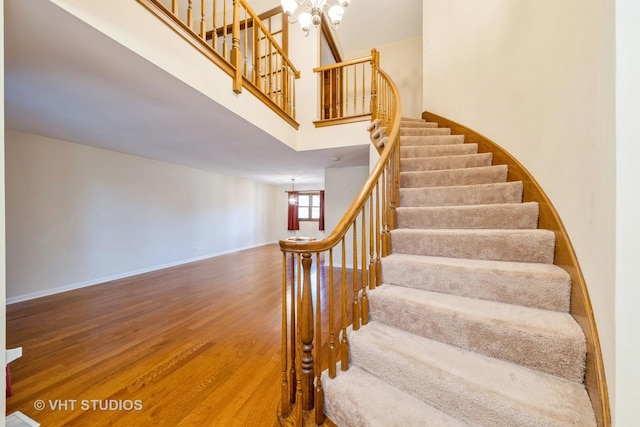 stairs featuring hardwood / wood-style floors, a high ceiling, and a notable chandelier