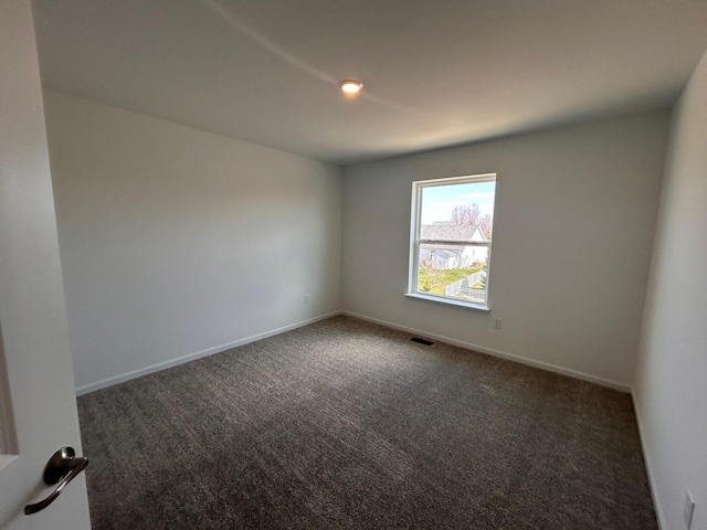 carpeted spare room with visible vents and baseboards