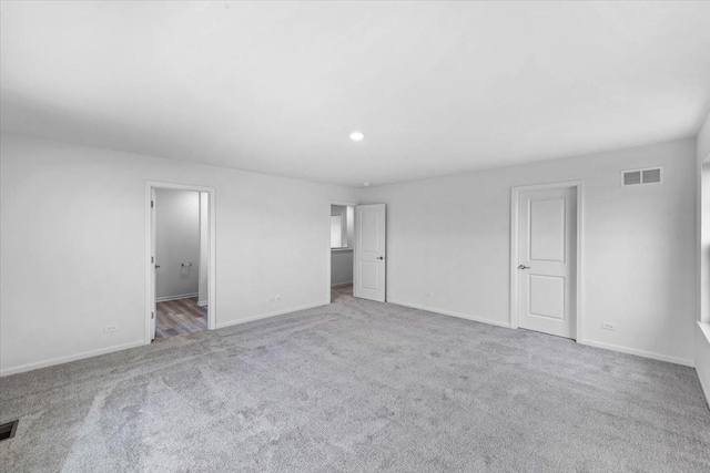 unfurnished bedroom with ensuite bathroom and light colored carpet