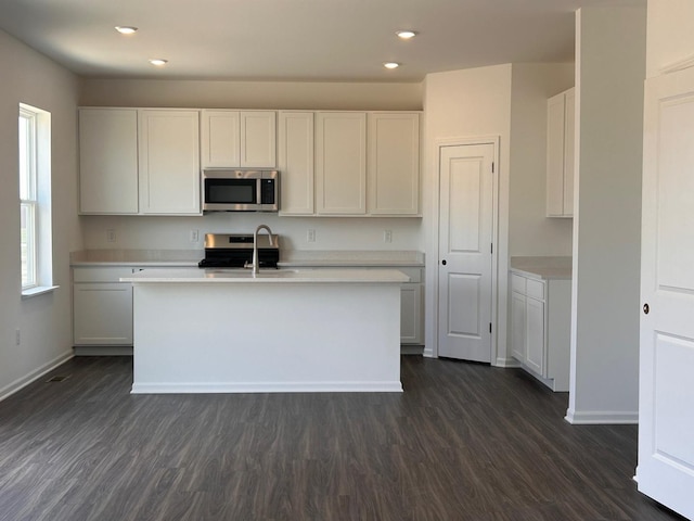 kitchen featuring appliances with stainless steel finishes, a sink, light countertops, and dark wood-style flooring