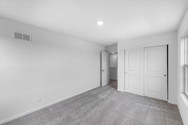 unfurnished bedroom with light carpet and a closet