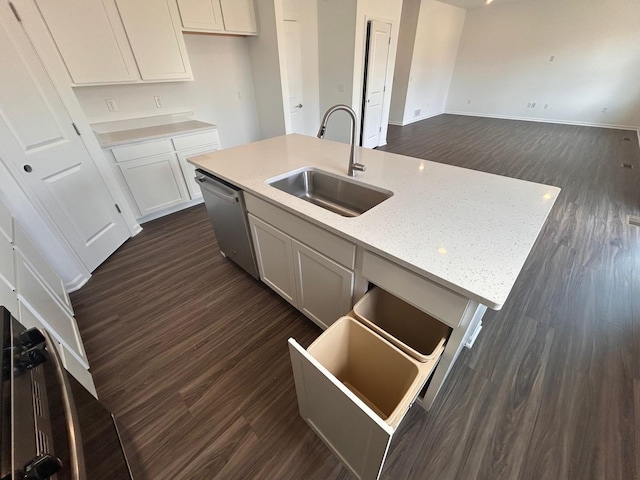 kitchen featuring stainless steel dishwasher, dark wood finished floors, a sink, a center island with sink, and baseboards