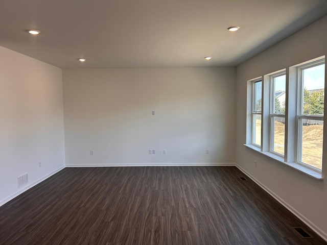 unfurnished room featuring dark wood-style flooring, baseboards, and visible vents