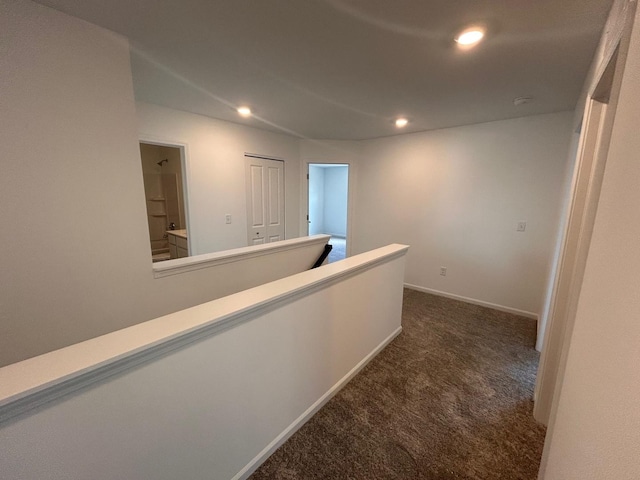 hallway featuring recessed lighting, dark colored carpet, and baseboards