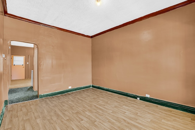 empty room featuring crown molding, light hardwood / wood-style flooring, and a textured ceiling