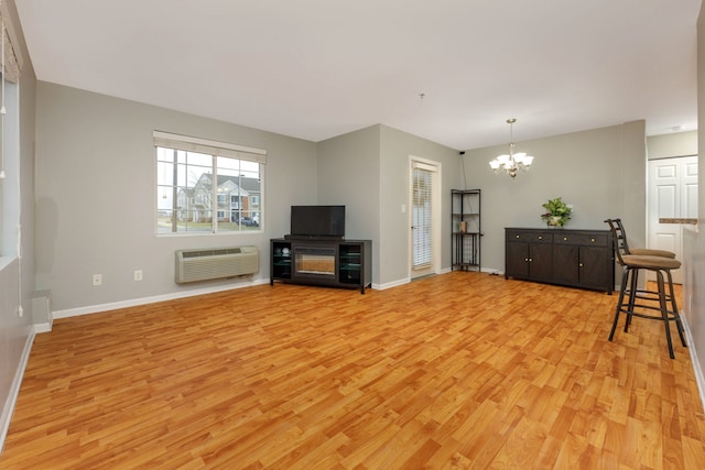 living room featuring an inviting chandelier, an AC wall unit, and light hardwood / wood-style flooring