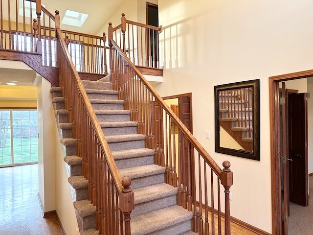 stairway featuring a skylight and high vaulted ceiling