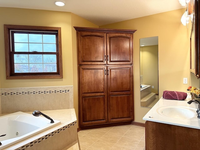 bathroom featuring tile patterned flooring, a relaxing tiled tub, and vanity