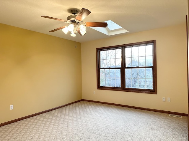 carpeted empty room with a skylight and ceiling fan