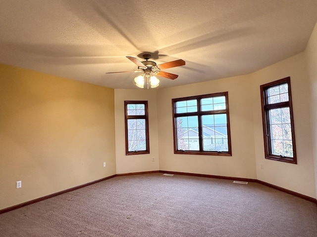 carpeted empty room with ceiling fan and a textured ceiling