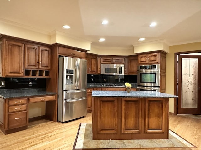 kitchen featuring a center island, light wood-type flooring, stainless steel appliances, and backsplash