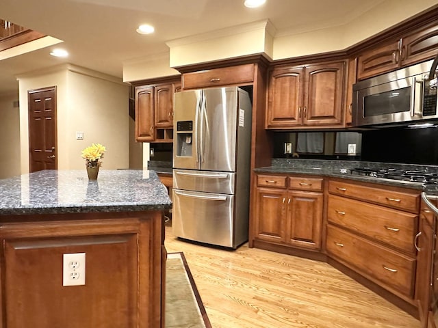 kitchen featuring dark stone counters, a kitchen island, light wood-type flooring, and appliances with stainless steel finishes