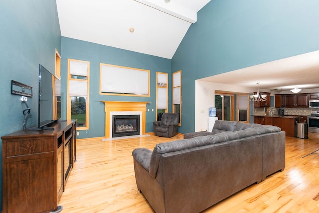 living room featuring a healthy amount of sunlight, beam ceiling, high vaulted ceiling, and light hardwood / wood-style flooring