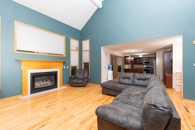 living room with beam ceiling, light wood-type flooring, and high vaulted ceiling