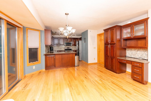 kitchen with appliances with stainless steel finishes, tasteful backsplash, pendant lighting, light hardwood / wood-style flooring, and a notable chandelier