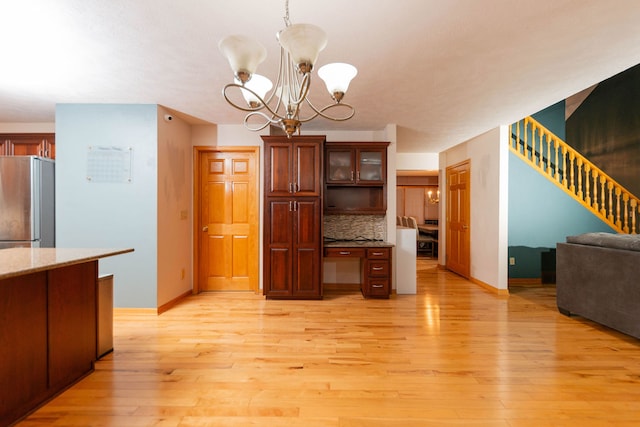 kitchen with an inviting chandelier, light hardwood / wood-style flooring, tasteful backsplash, decorative light fixtures, and stainless steel refrigerator