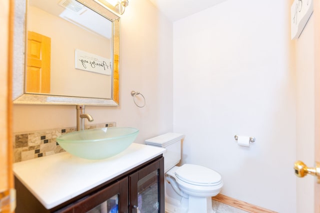 bathroom featuring vanity, toilet, and tasteful backsplash