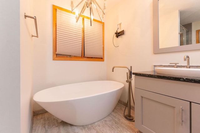 bathroom featuring a bathing tub, vanity, wood-type flooring, and a notable chandelier