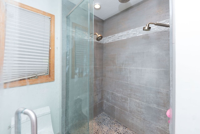 bathroom featuring toilet, an enclosed shower, and a textured ceiling