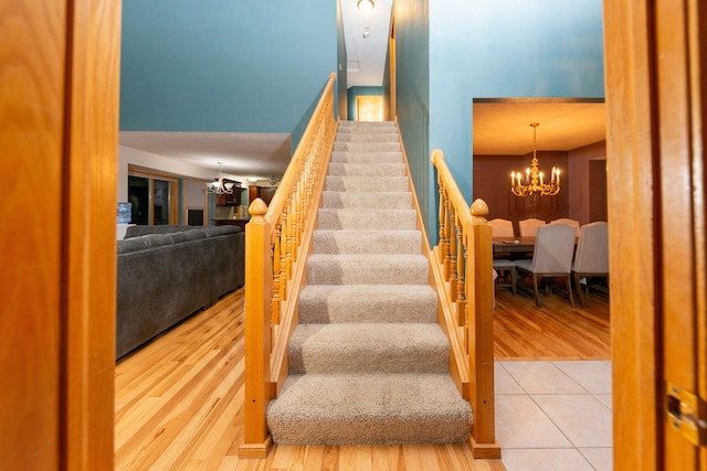 stairs featuring hardwood / wood-style flooring and a chandelier