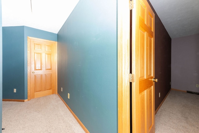 corridor with lofted ceiling and light carpet