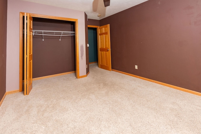 unfurnished bedroom with ceiling fan, a closet, and light colored carpet