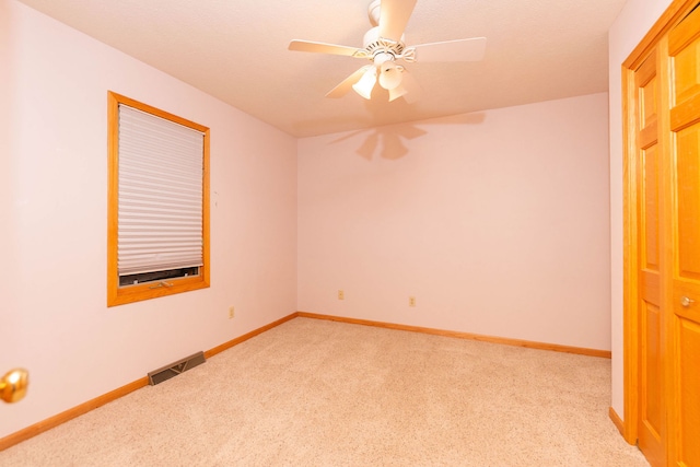 unfurnished room featuring ceiling fan, light colored carpet, and a textured ceiling