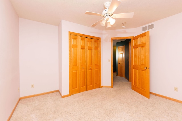 unfurnished bedroom with ceiling fan, a closet, light carpet, and a textured ceiling