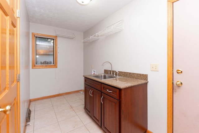 kitchen with a textured ceiling, light tile patterned floors, and sink