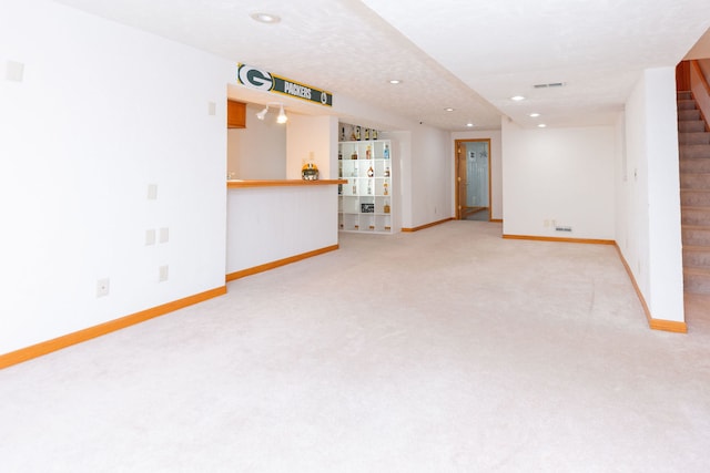 unfurnished living room featuring a textured ceiling and light colored carpet