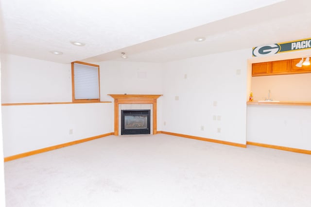 unfurnished living room with a fireplace, light colored carpet, and sink