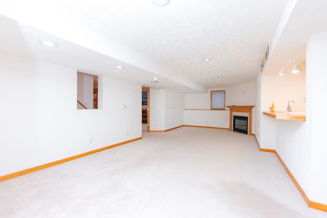 unfurnished living room featuring a tile fireplace, a textured ceiling, and light colored carpet