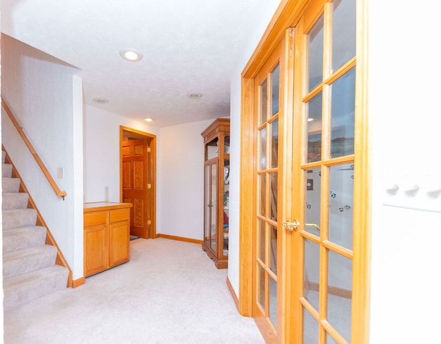 hall with french doors and light colored carpet