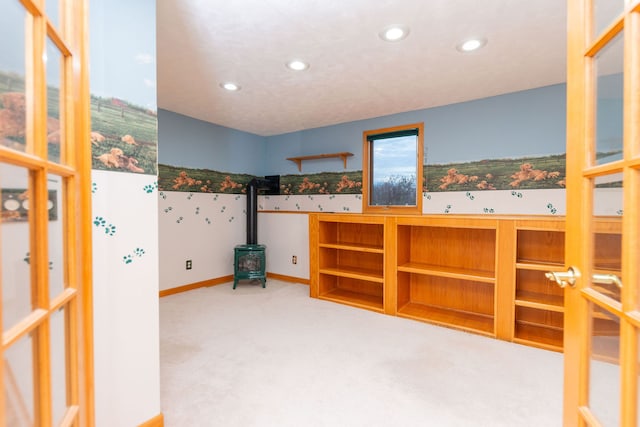 unfurnished bedroom featuring a wood stove and carpet