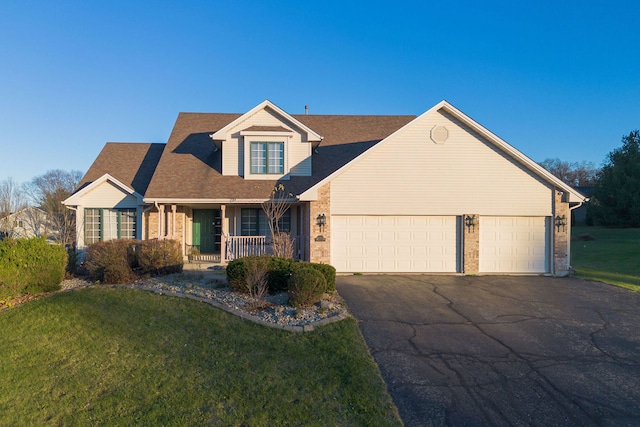 view of front of house with covered porch, a front yard, and a garage