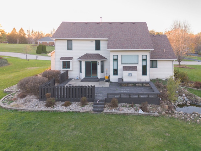 back house at dusk with a yard and a wooden deck