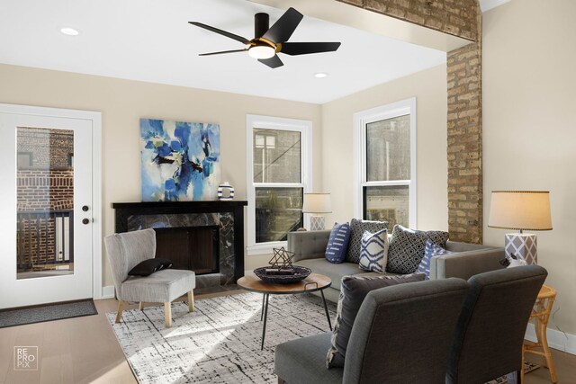 living area with a premium fireplace, a ceiling fan, wood finished floors, and recessed lighting