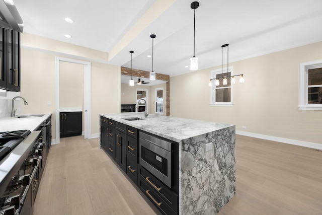 kitchen featuring stainless steel appliances, sink, a kitchen island with sink, and decorative light fixtures