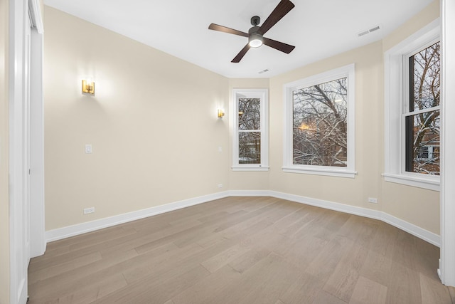 spare room with ceiling fan, light wood finished floors, visible vents, and baseboards