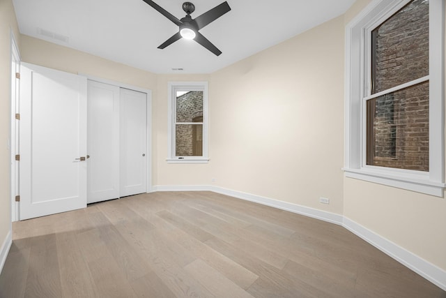 unfurnished bedroom featuring ceiling fan, a closet, and light wood-type flooring