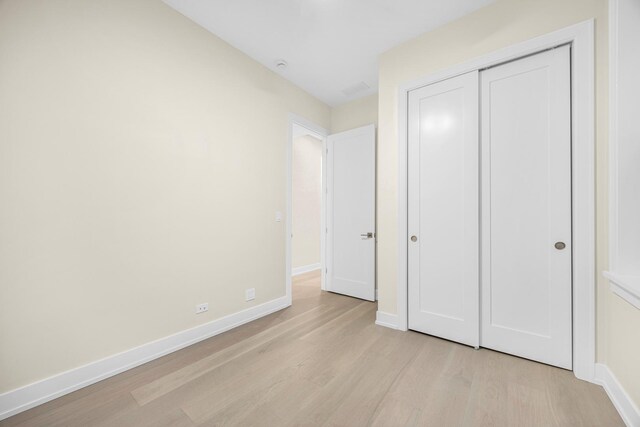 unfurnished bedroom with a closet and light hardwood / wood-style flooring