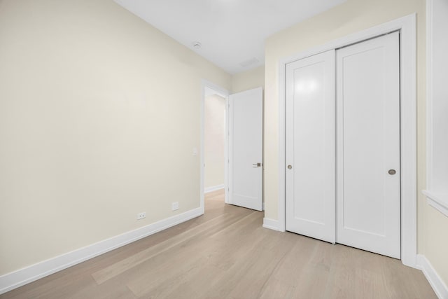 unfurnished bedroom with a closet, light wood-type flooring, and baseboards