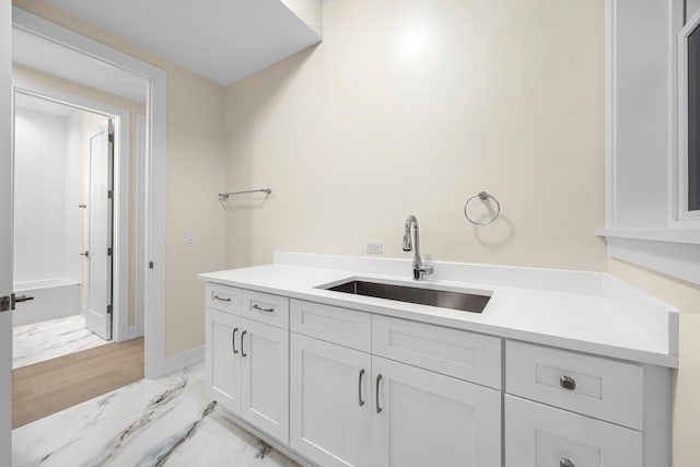 full bathroom with marble finish floor, a bathing tub, vanity, and baseboards