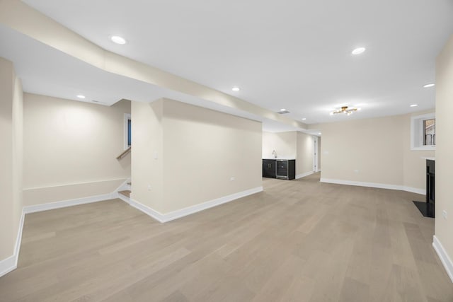 finished basement with recessed lighting, stairway, a fireplace with flush hearth, light wood-style floors, and baseboards