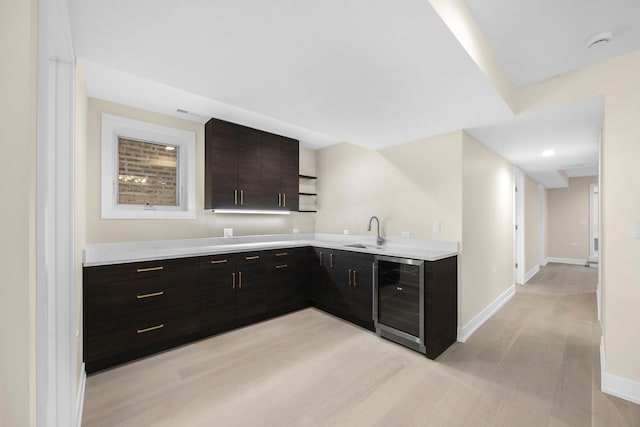 kitchen featuring wine cooler, a sink, baseboards, light countertops, and open shelves