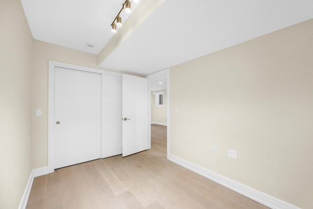 unfurnished bedroom with light wood-style floors, baseboards, and a closet
